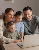Eine Familie mit Tochter und Sohn betrachten gemeinsam lächelnd einen Laptop (KI-generiertes Bild)
