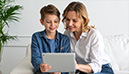 Mutter und Sohn betrachten gemeinsam lächelnd ein Tablet (KI-generiertes Bild)